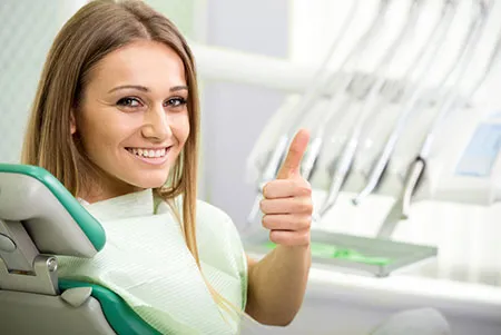 smiling patient in dental chair giving a thumbs up